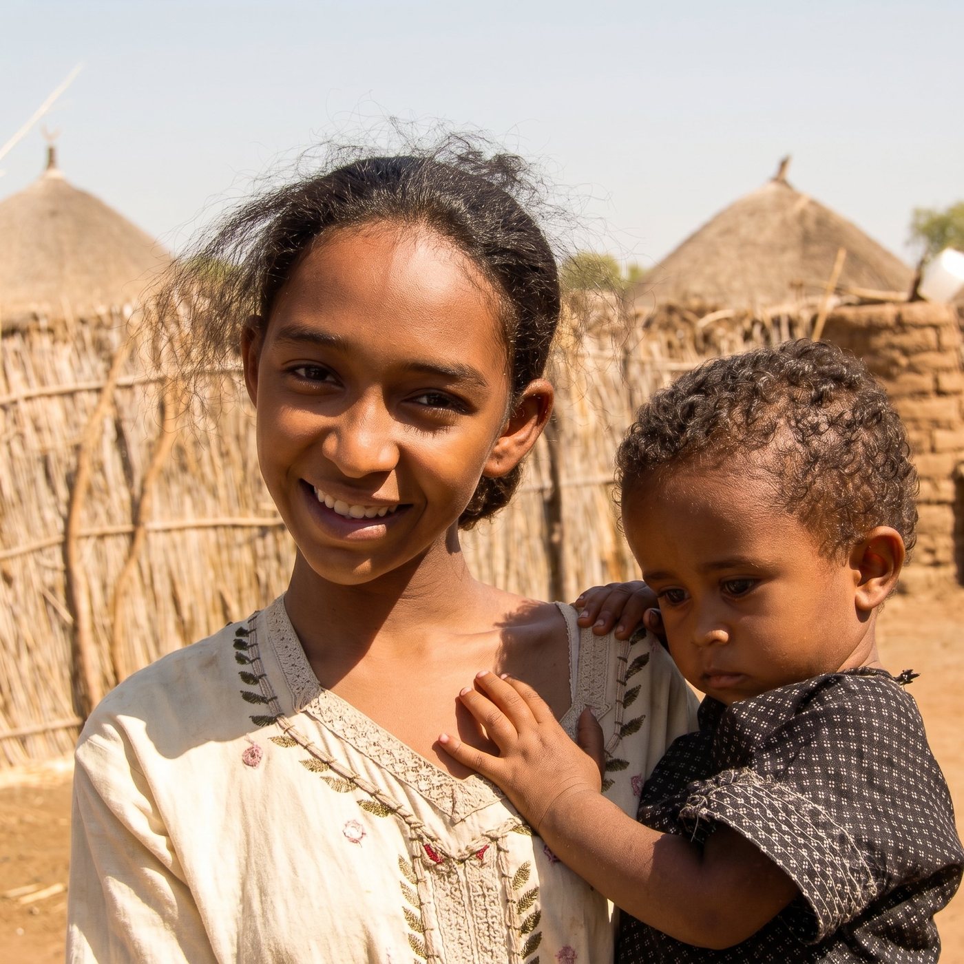 A young woman and child in a gum-belt village — the families the harvest sustains