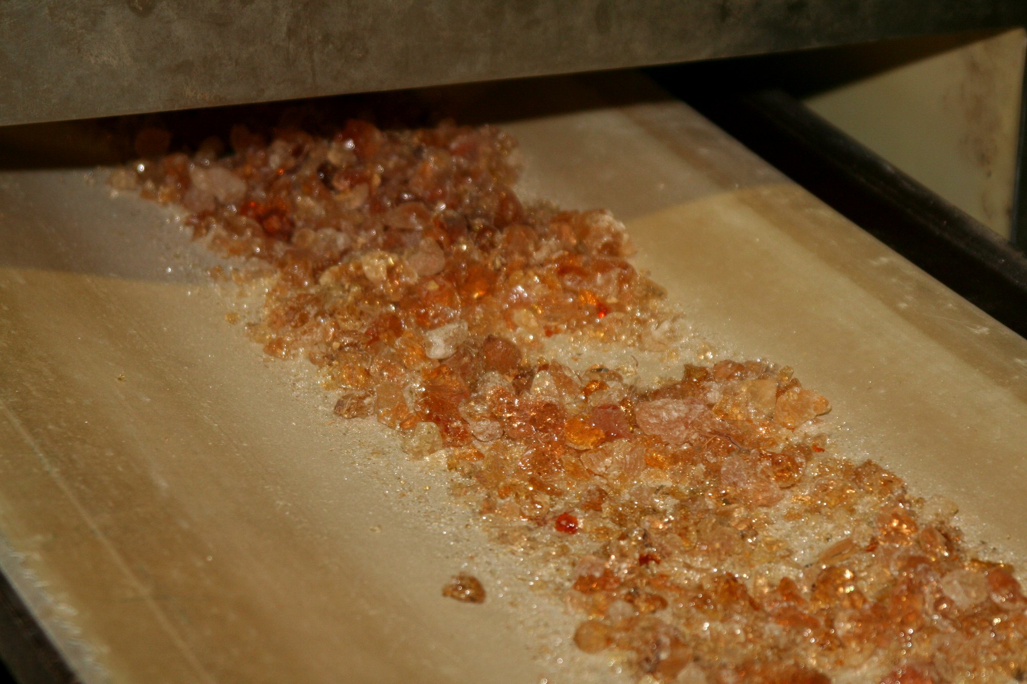 Close-up of kibbled amber acacia gum moving along a conveyor at origin