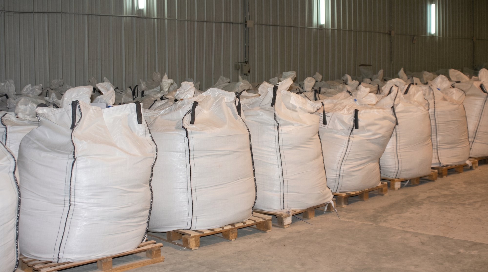 Rows of filled one-ton big bags of gum arabic on pallets in an origin warehouse
